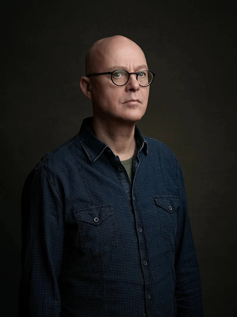 Clean studio portrait of a woman in a black t-shirt against a grey background.